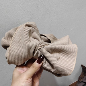 Close-up of khaki knitted headband showing large bow design and vertical ribbed texture