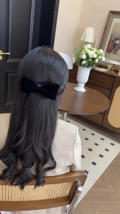 Detailed back view of a black velvet bow hair clip worn on elegant dark curly hair