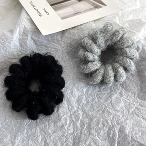 Detailed texture of gray and black wool-like spiral hair ties on fashion magazine background