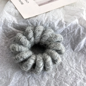 Macro shot of gray plush spiral hair tie with fluffy wool texture on white background