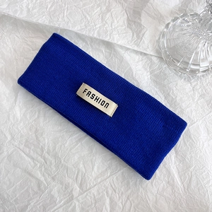 Dettaglio della fascia in maglia blu Klein con un'etichetta tessuta FASHION bianca
