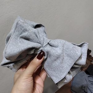 Close-up of grey knitted headband featuring a large bow with soft ribbed texture