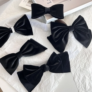 Close-up detail of five elegant black silk velvet bow hair clips with pearl accents