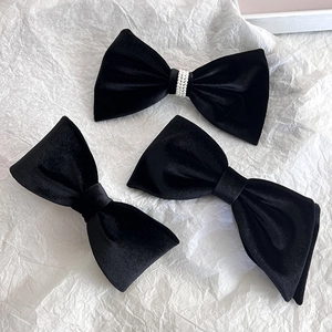 Detail of elegant black velvet hair bow clips with pearl embellishment on white background