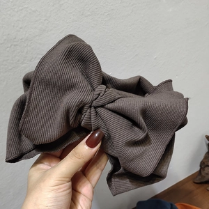Close-up of a brown oversized knitted bow headband with soft ribbed fabric texture