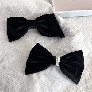 Detail of elegant black velvet bow hair clips with lustrous white pearl accents