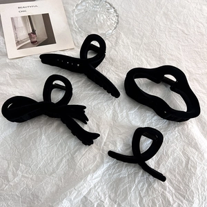 Set of four black flocked hair claws in geometric shapes on minimalist white background