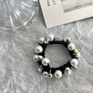 Détail de l'élastique à cheveux fait main avec perles blanches et charms dorés