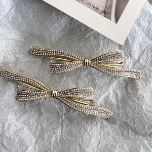 Elegante goldene Bogenspangen mit Perlen und Strasssteinen auf strukturiertem Papier