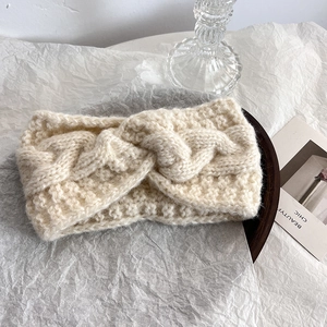 Dettaglio della fascia in maglia beige con nodo a torsione e trame a treccia