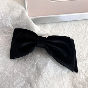 Detailed close-up of a premium black velvet bow hair clip on a textured background