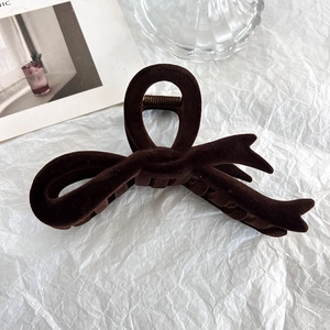 Macro shot of dark brown flocked hair claw clip with velvet bow on white paper