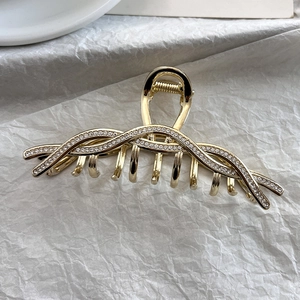 Detailaufnahme der Haarklammer aus goldener Legierung mit funkelnden Strasssteinen und Feder