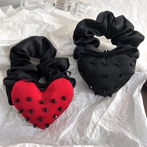 Detail of red and black heart hair ties made with smooth black satin fabric and studs