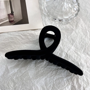 Close-up of a black flocked hair claw clip with a velvet texture and elegant crossed design