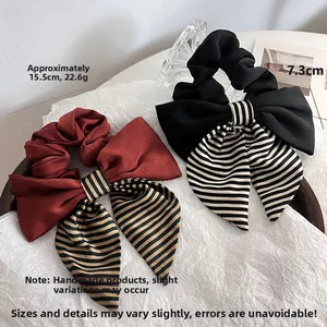 Detail view of large bow hair scrunchies with striped texture in burgundy and black tones