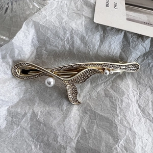 Detail einer eleganten Gold-Fischschwanz-Haarspange mit Strasssteinen und Perlen