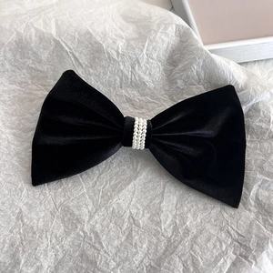 Detailed macro view of black velvet bow hair clip with elegant triple-row pearl inlay