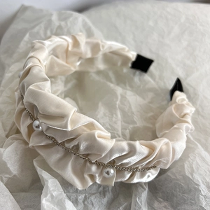 Detail of cream pleated satin headband with sparkling rhinestones and white pearls