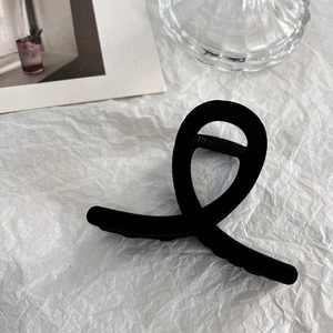 Detailed close-up of a minimalist black flocked hair claw clip with a textured velvet surface