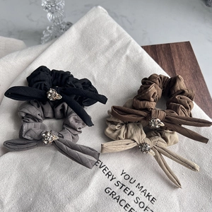 Close-up of quilted bow hair ties with sparkling crystal accents in four neutral colors