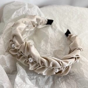 Detailed macro view of pleated champagne satin headband with pearls and silver rhinestones