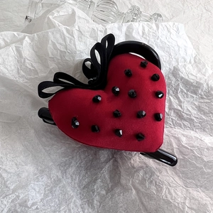 Detailed view of a red velvet heart hair claw with black crystals and a ribbon bow