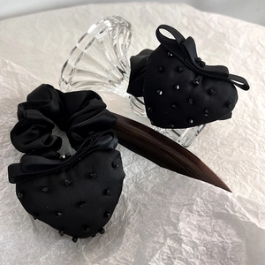 Detail of elegant black heart-shaped satin scrunchies with beads and bow accents