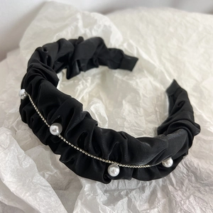 Detail of elegant black pleated fabric headband with shiny pearls and rhinestone chain