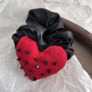 Close-up of a black satin hair tie featuring a red velvet heart with black beads