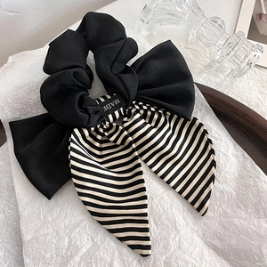 Detail of a black and white striped satin bow scrunchie with elegant long ribbon tassels