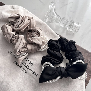 Detailed shot of champagne and black satin bow scrunchies with white faux pearls