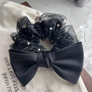 Detailed view of elegant black bow hair scrunchie with silver sequins and satin texture