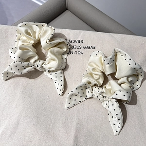 Close-up of cream satin scrunchies with black polka dots and chic bow tie detail
