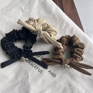 Detail of bow hair ties in black, beige, and brown with vintage rhinestone buckles