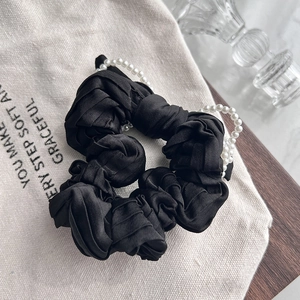 Elegant black satin scrunchie with pearl bow detail shown on a neutral background