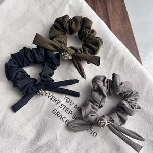 Detail of handcrafted fabric bow hair ties with Czech rhinestones in olive, black, and grey
