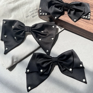 Details eleganter schwarzer Satin-Haarspangen mit weißen Perlen und Federverschluss
