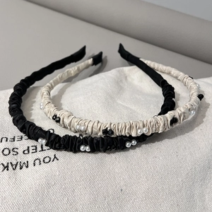 Détail de serre-têtes en satin plissé avec élégantes perles et ornements noirs