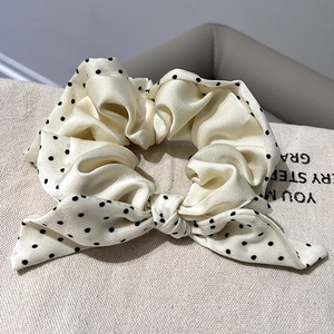 Detail of cream satin scrunchie with black polka dots and an elegant bow knot