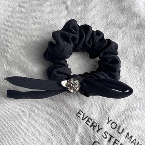 Detail of black chiffon bow hair tie featuring a large sparkling central rhinestone