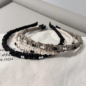 Détail de serre-têtes en satin plissé avec perles en tons noir, beige et marron