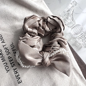Close-up of champagne satin bow hair tie with elegant white pearls and silk texture