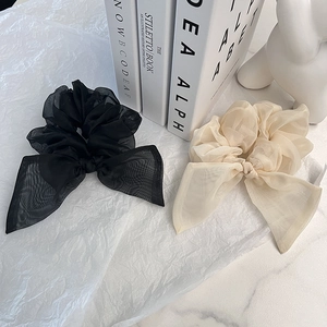Détail de chouchous à nœuds en organza noir et beige sur un fond décoratif élégant