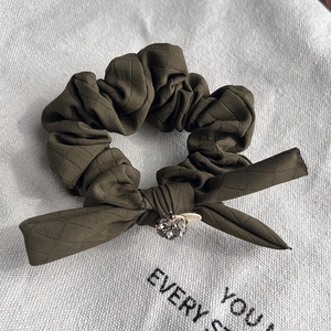 Detailed macro shot of olive green plaid bow hair tie with sparkling rhinestone decor