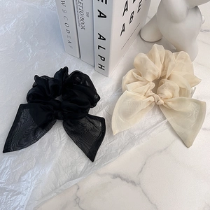 Détail de chouchous élégants en organza avec grand nœud en noir et beige crème doux
