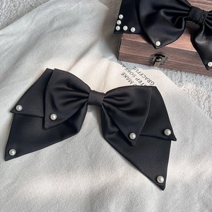 Details eleganter schwarzer Satin-Haarschleifen mit weißen Perlen auf rustikalem Holzdekor