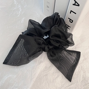 Chouchou élégant en organza noir avec nœud papillon sur un fond blanc texturé