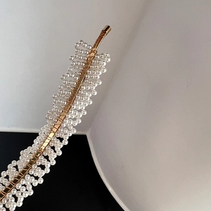 Macro detail of elegant handmade pearl headband with woven gold wire and white beads