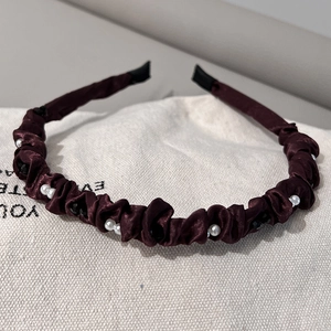 Détail d'un serre-tête en satin plissé bordeaux avec perles et strass